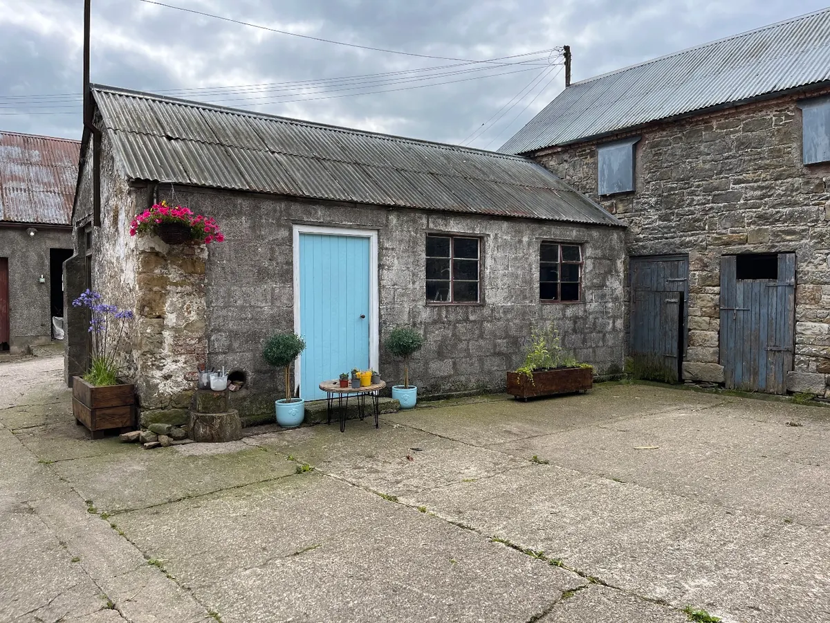 The farmyard with the shed's new pale blue door and tubs of flowers