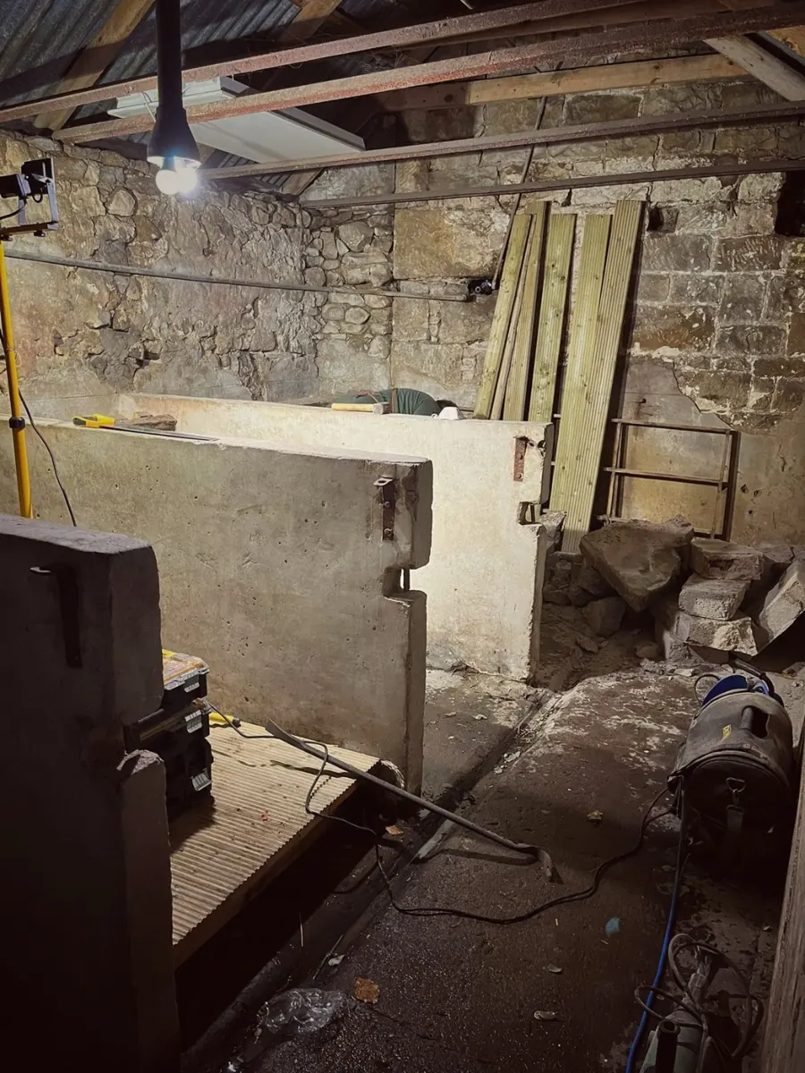 Inside before the work: old stalls and rubble under the corrugated roof