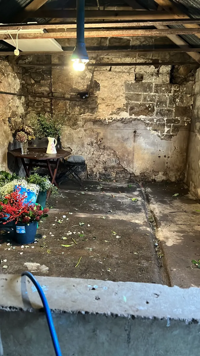 Bare stone walls inside, with flowers waiting by the door