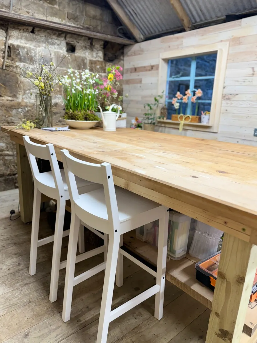 A long wooden table and white chairs set out for events