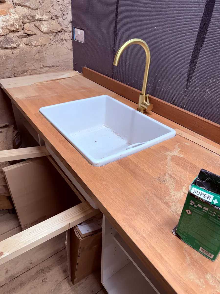 A white Belfast sink set into a wooden worktop with a brass tap